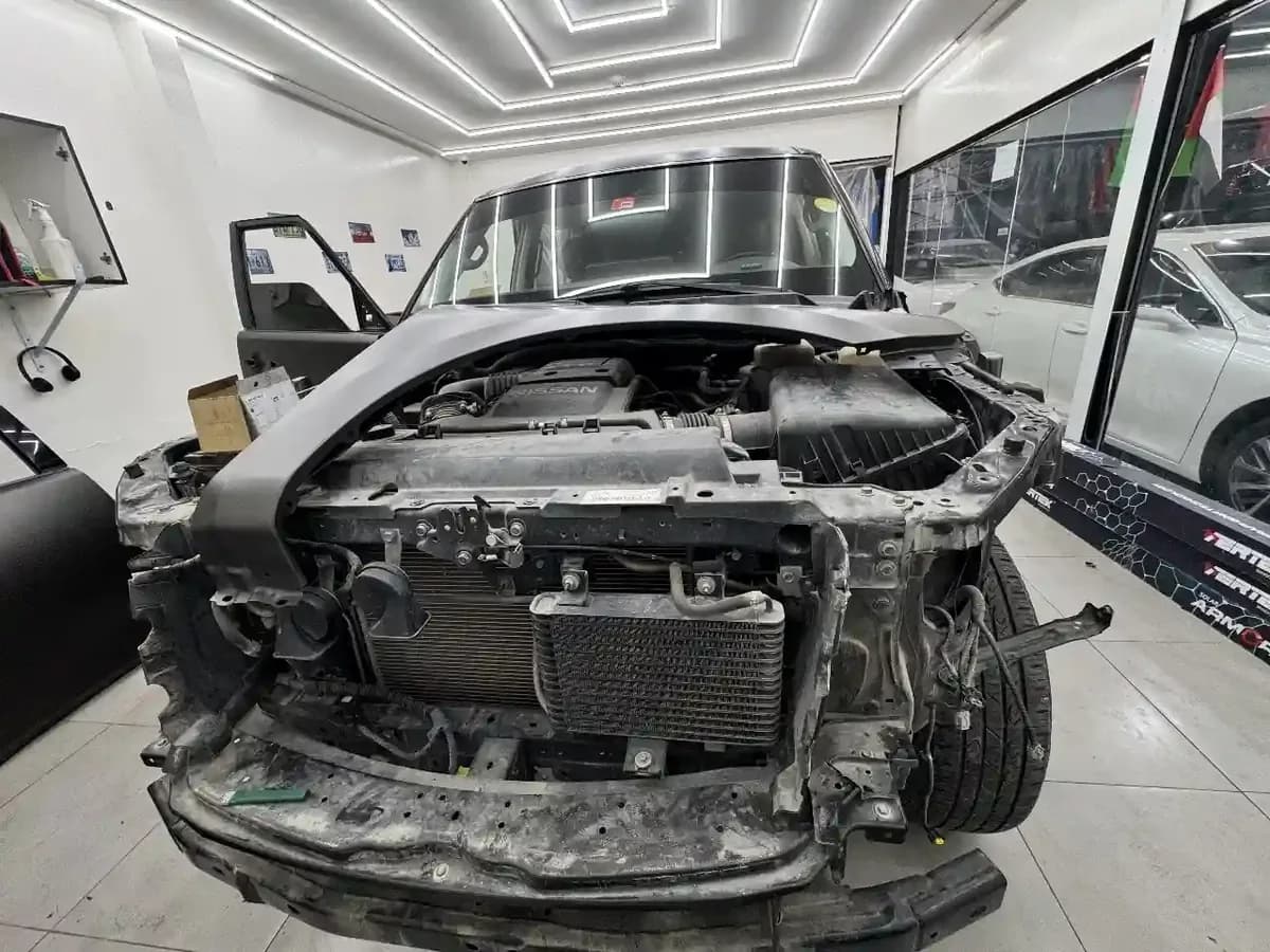 A vehicle with its front end stripped down for major mechanical work at the Musaffah workshop